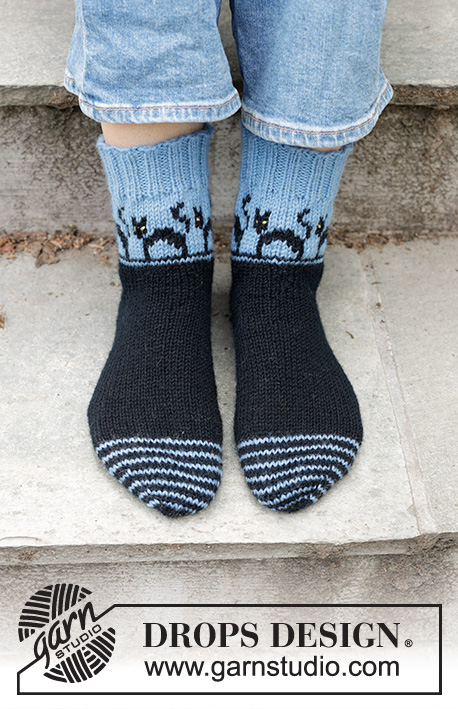 Spooky Evening Socks / DROPS 244-45 - Strikkede sokker i DROPS Karisma. Arbejdet strikkes tå op med flerfarvet mønster med katte og kilehæl. Størrelse 35-43. Tema: Halloween.