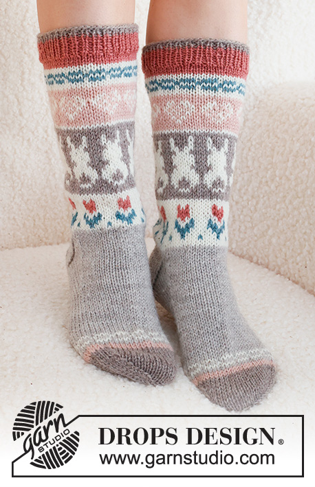 Dancing Bunny Socks / DROPS 229-34 - Strikkede sokker i DROPS Karisma. Arbeidet strikkes ovenfra og ned, i glattstrikk med flerfarget mønster med hjerte, hare / påskehare og blomst. Størrelse 35 - 46. Tema: Påske.