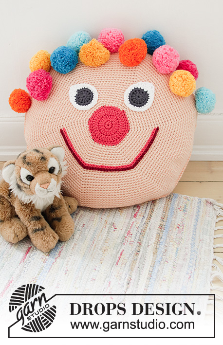 Bongo the Clown Pillow / DROPS Children 35-1 - Crocheted clown: round pillow casing with pompoms for children, crocheted in the round from center outwards. Piece is crocheted in DROPS Paris.